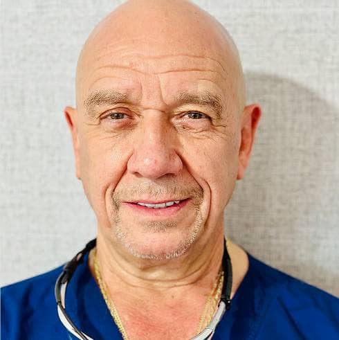 fifthavenuesmile | Portrait of a dentist wearing navy scrubs with a stethoscope around his neck