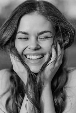 fifthavenuesmile | Black and white photo of a young woman smiling with eyes closed and hands on her cheeks